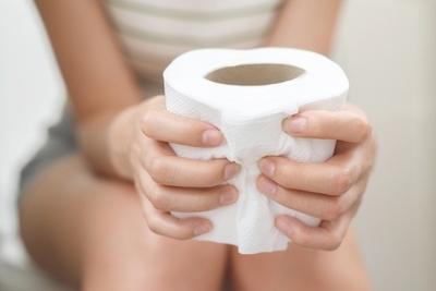 Woman suffering from Constipation holding a toilet paper