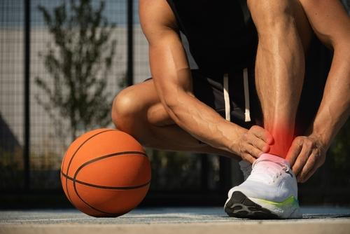A basketball player clutching his ankle after reinjury caused by an unhealed sprain.