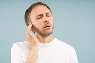 Man experiencing ear congestion after recovering from a summer cold