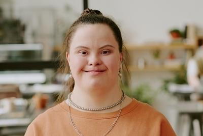 Brown shirt girl with Down Syndrome looking in camera