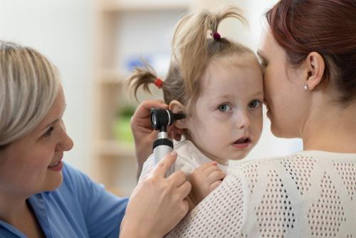 Pediatrician-checking-the-young-girl-ear-with-mother-on-clinic.