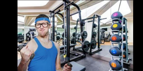 A nerdy guy in black glasses and a blue muscle shirt lifting stressing over lifting small dumbbell weights in s gym in Raleigh NC