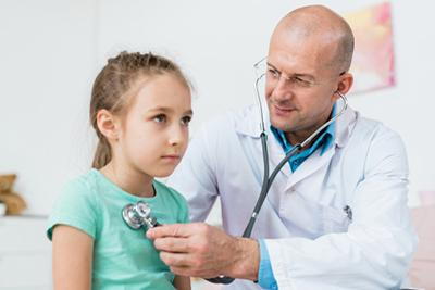 Doctor checking the heartbeat of a young girl.