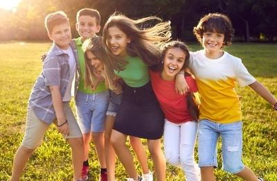 Smiling-Kids-Hugging-Outdoors-In-a-Sunny-Green-Park