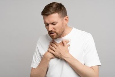 Man-in-white-shirt-clutching-chest-in-discomfort