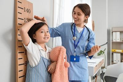 Healthcare professional assessing growth of child during pediatric developmental checkup
