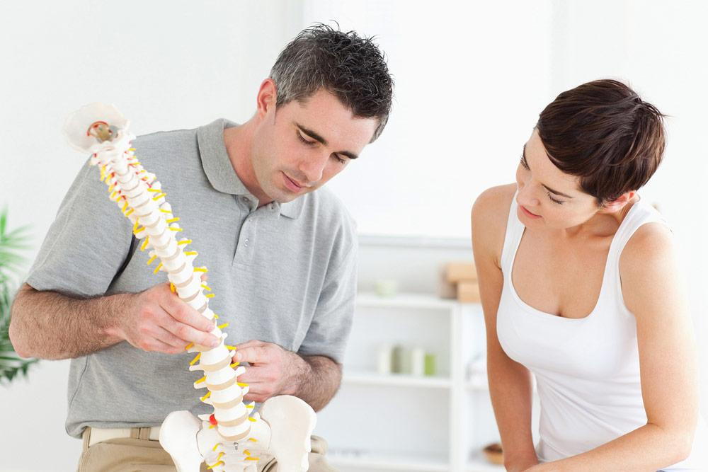 man showing a woman a spine model