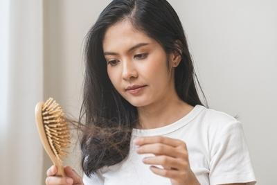Woman looking in comb with a lot of hair loss