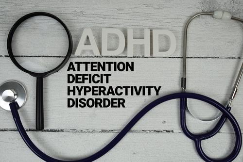 Text reading "Attention Deficit Hyperactivity Disorder" with a stethoscope and magnifying glass representing medical evaluation.