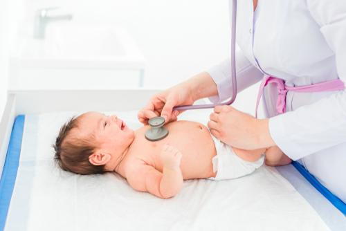A pediatrician examining and caring for a newborn baby during a routine checkup.
