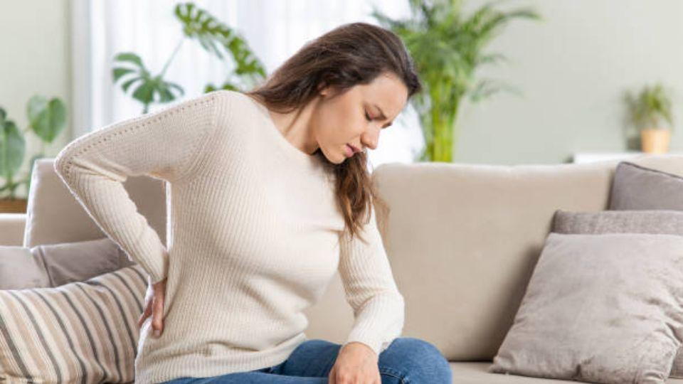 Women Sitting On Couch Suffering From Back Pain