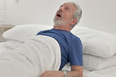 Old man having a bad nightmare on bed