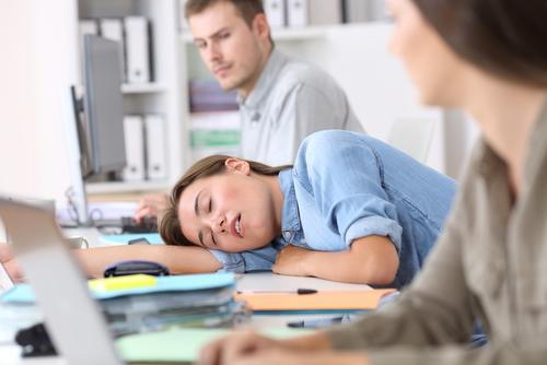 Woman with narcolepsy falling asleep at her desk during work hours