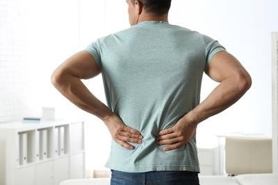 Man-holding-his-back-feeling-in-pain-with-gray-shirt.