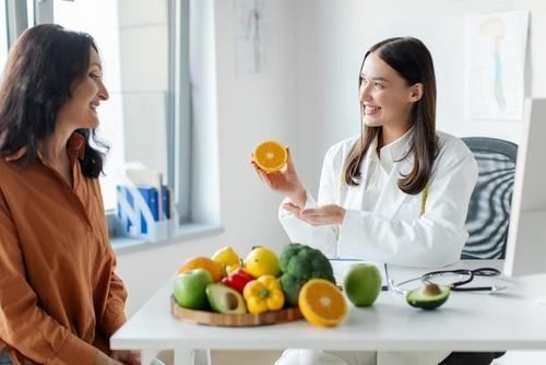 A chiropractor providing nutritional counseling to a female patient in a clinic.