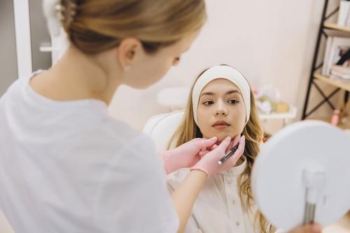 Female client looking at her face after receiving a dermal filler injection.