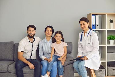 Doctor and family sitting on sofa smiling on camera