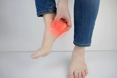 Woman holding her heel due to pain or discomfort.