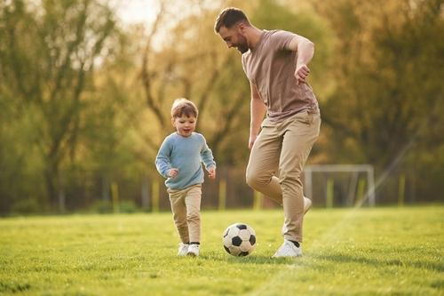 A father encouraging his son to engage in physical activity by playing soccer together.