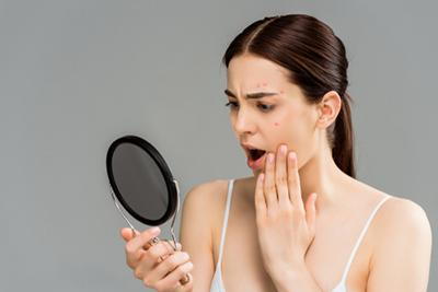 Woman looking on mirror feeling disapointed