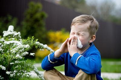 Young boy wiping his nose from sneezing outdoor