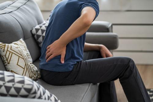 Visible signs of sciatic discomfort in man sitting on couch