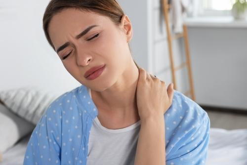 Woman holding her neck in pain while sitting at home