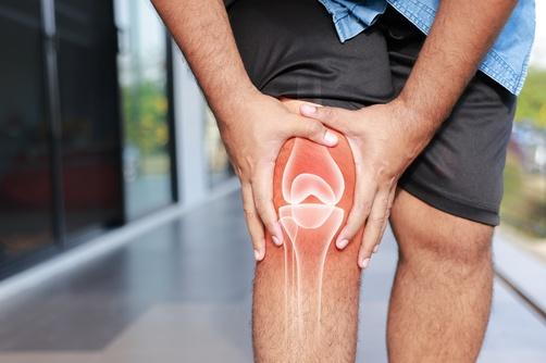 A man holding his knee, experiencing pain caused by arthritis.