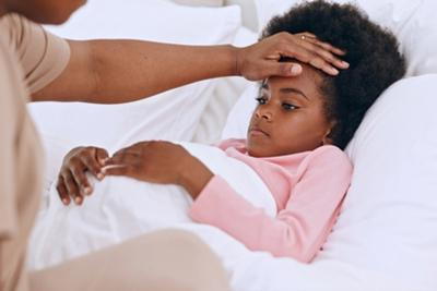 Mother assessing her child's fever by touching the forehead.