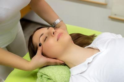 A woman is massaged by the therapist on her head while lying down.