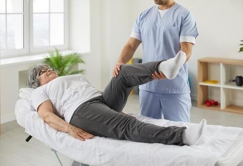 Therapist streching the leg of an old woman