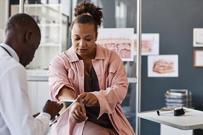 Dermatologist examining female patient’s skin rash