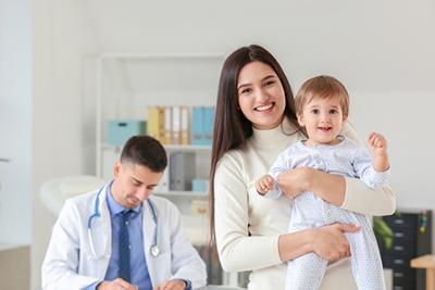 Young boy and a mother smiling with doctor in the background.