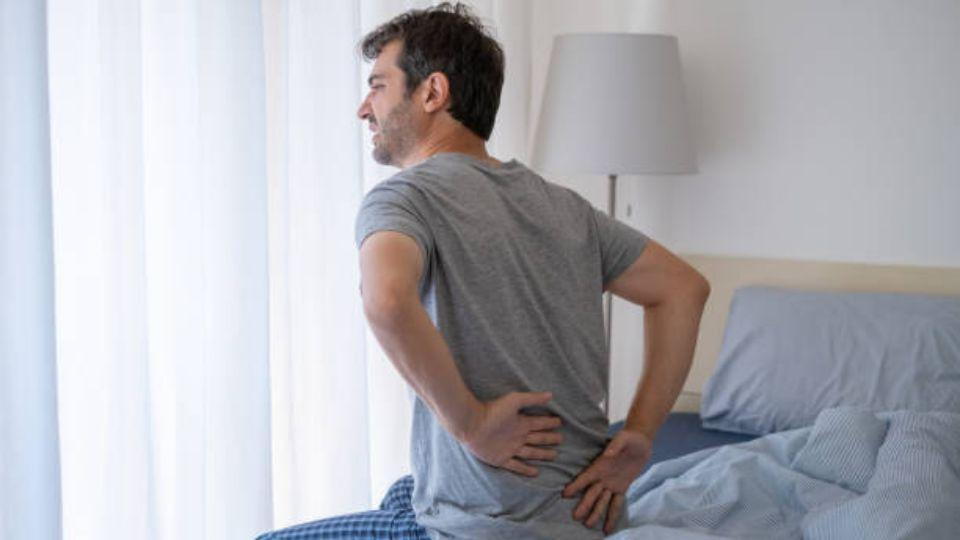 Man Sitting On Bed With Back Pain