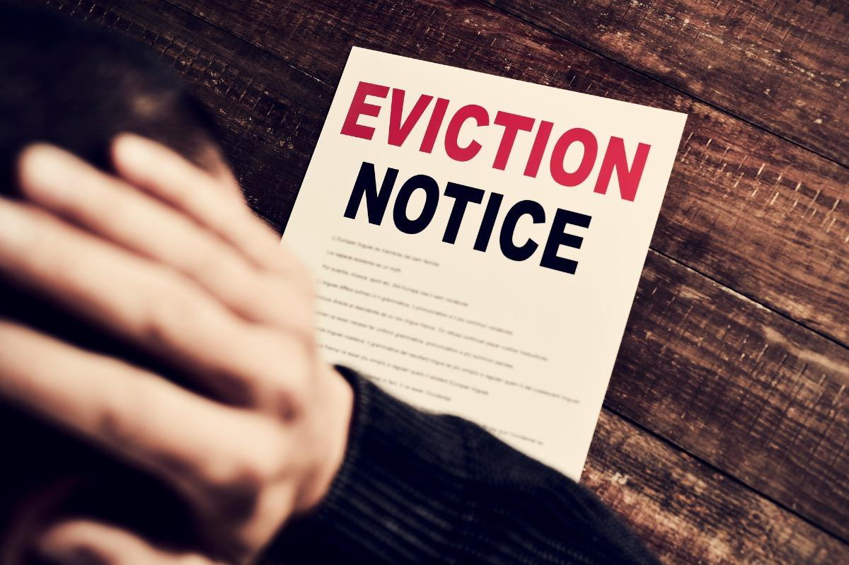 A person holds their head in dismay as they look at a piece of paper reading 'Eviction Notice.'