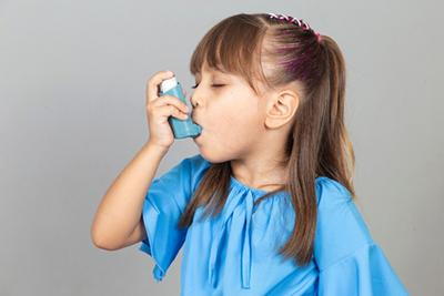 Young girl with inhaher in her mouth due to asthma.