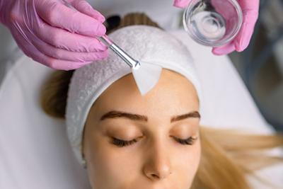 Woman receiving professional chemical peel on her face.