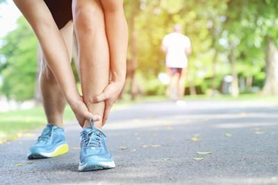 Sport person holding ankle in pain outdoor.