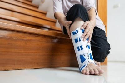 Senior suffering from foot fracture sitting on sofa