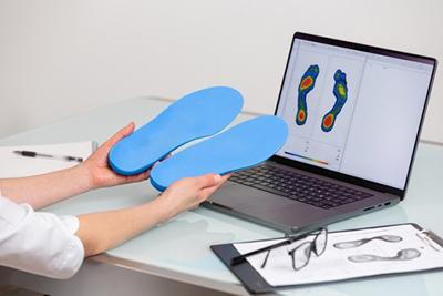 Custom foot orthotics infront of the laptop held by the doctor