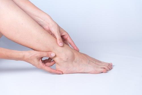 A woman holding her ankle due to pain and discomfort.