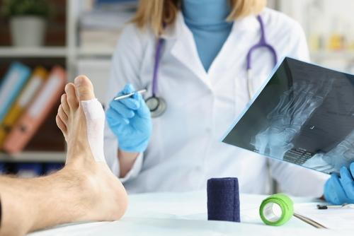A podiatrist examining a patient’s foot while reviewing X-ray results.