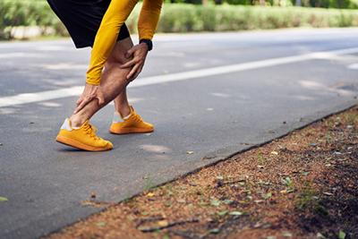 Runner Suffering from Achilles Tendonitis beside the road