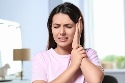 Woman holding her ear feeling in pain.
