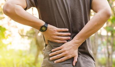 Man-holding-his-back-both-hands-outside