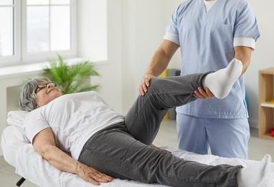 Doctor-checking-the-foot-of-patient-in-medical-bed.