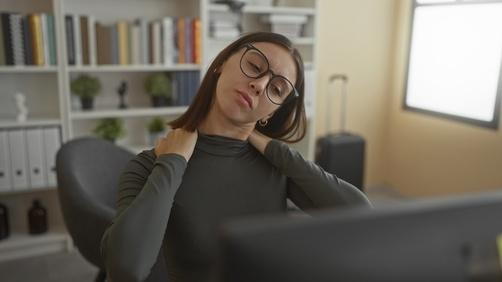 A woman performing neck stretches at home to relieve stiffness or tension.