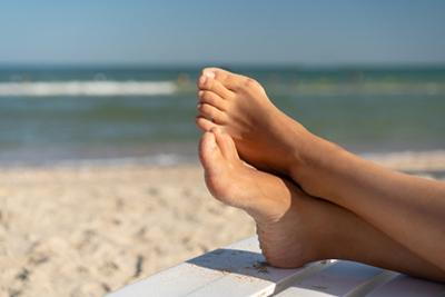 Woman relaxing at the beach with a foot affected by bunion