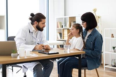 Pediatrician examining a young allergic child experiencing coughing symptoms.
