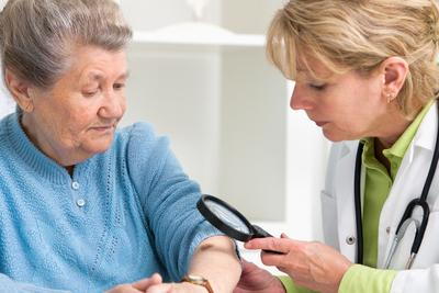 Old-woman-being-check-by-the-doctor-in-skin-with-magnifying-glass.